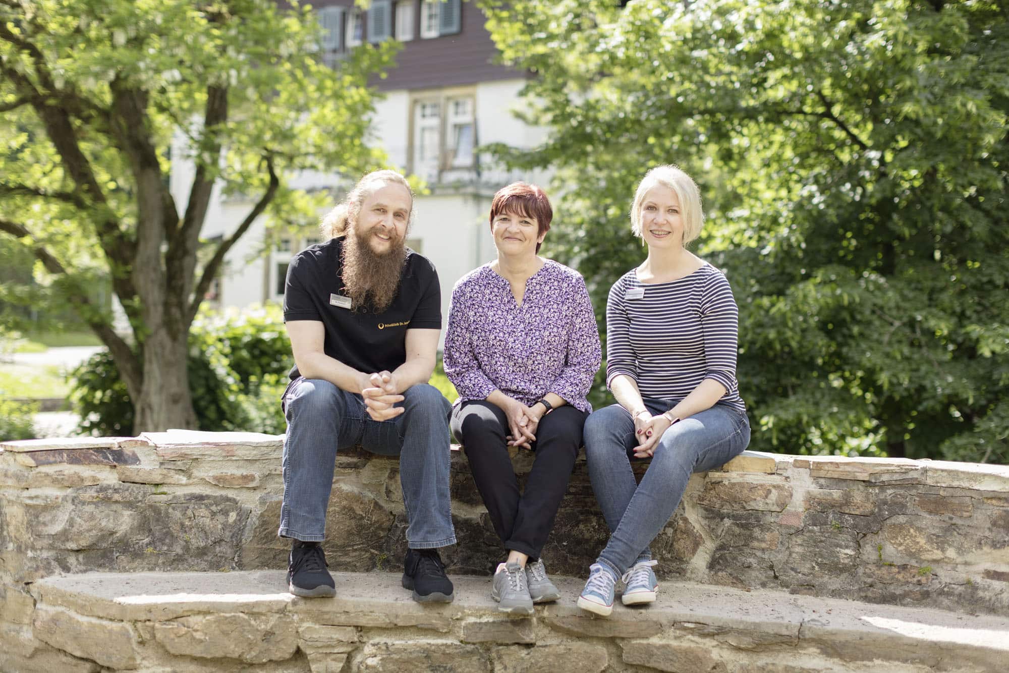 3 Mitarbeiter der Klinik für Burnout blicken lächelnd in die Kamera